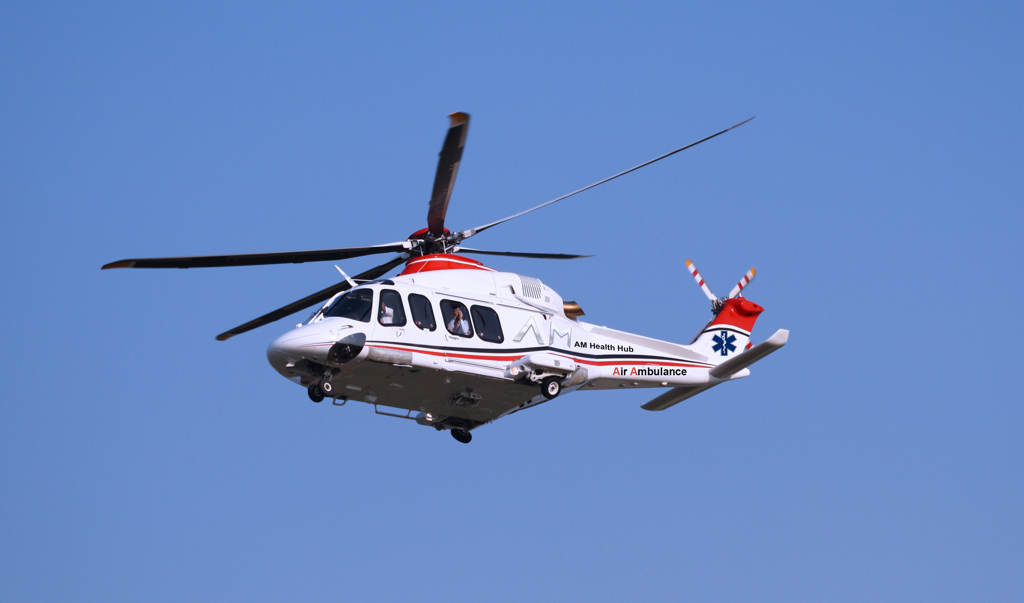 East Anglian Air Ambulance helicopter in flight against blue sky
